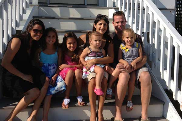 An au pair sits on steps with a host family and chidlren