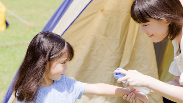 Child with carer applying insect repellent.