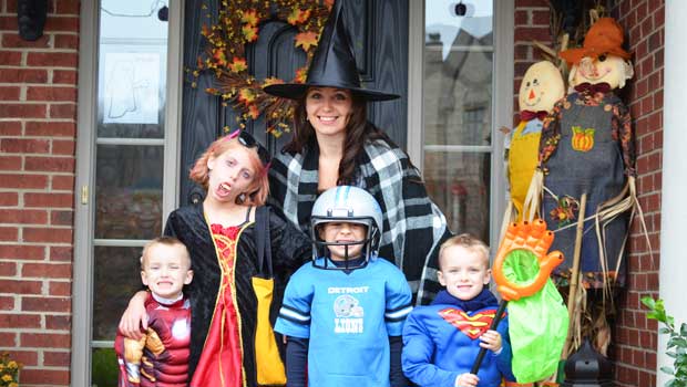 au pair, dressed as witch, with children in Halloween costumes