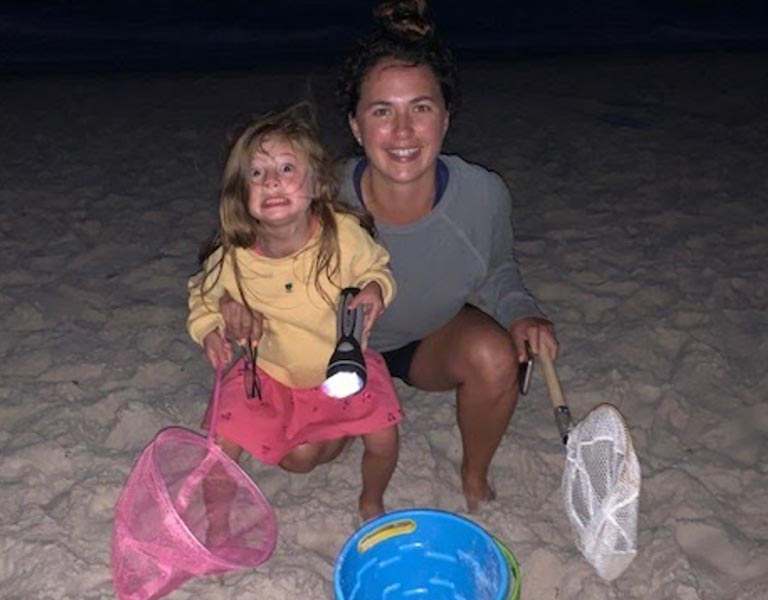 Au pair and host child on beach at night