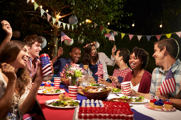 People seated at a table with U.S. flags and red, white, and blue food and cups.