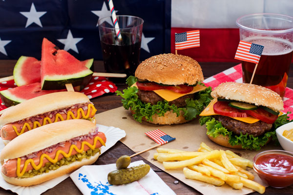 A table with U.S. flags and a red, white, and blue theme, along with hotdogs and hamburgers.