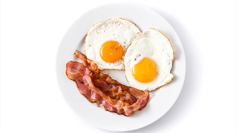 A plate of bacon and sunny-side-up eggs.