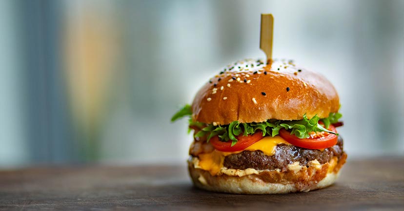 A hamburger with lettuce, tomatoes, and cheese.