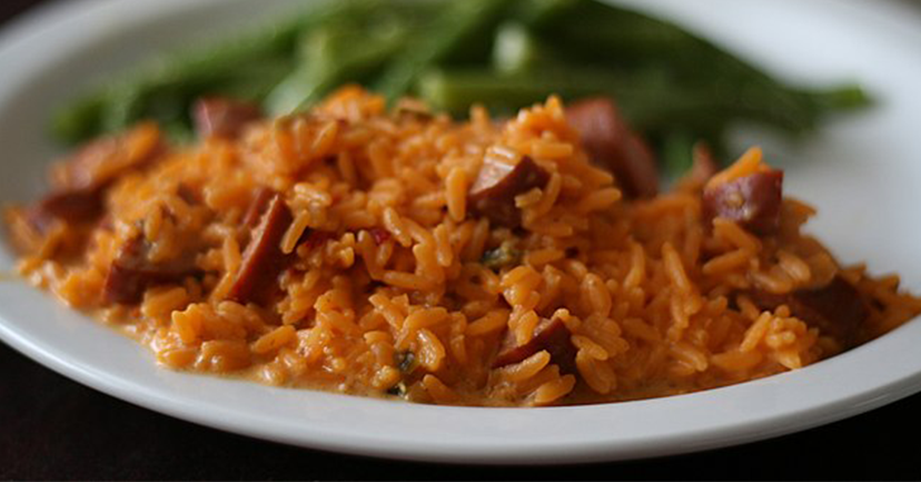 A plate with rice, sausages, and vegetables. 