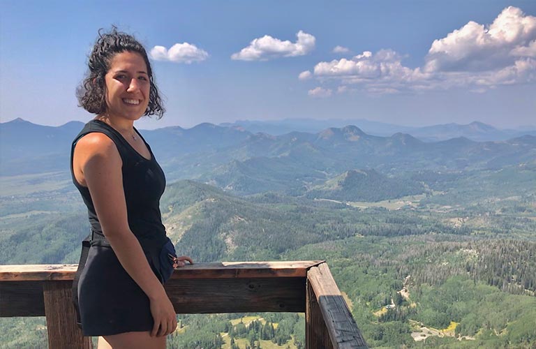 An au pair stands on an observation deck, looking out over mountains in the U.S. state of Colorado. 