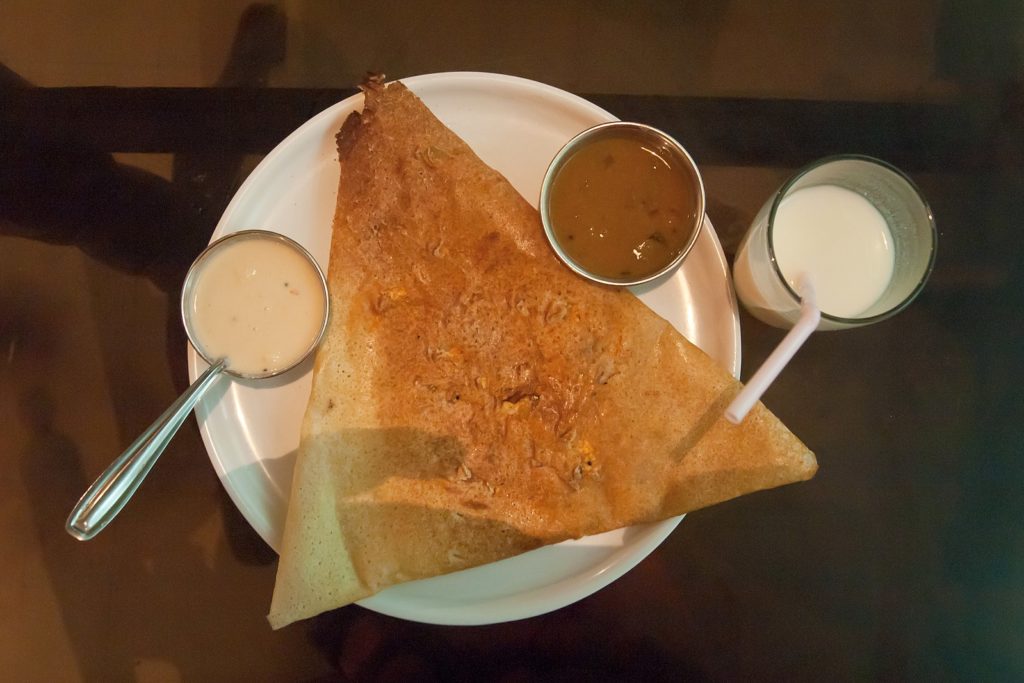 Indian dosa on a plate with sauce, representing holiday traditions.