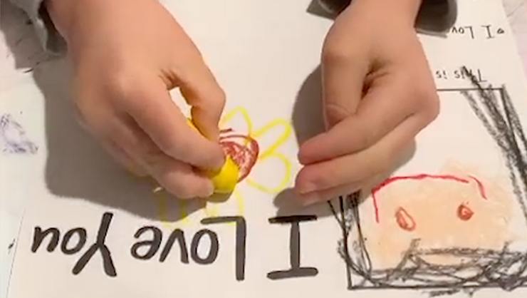 An au pair guides her host kid in making a Mother's Day card.