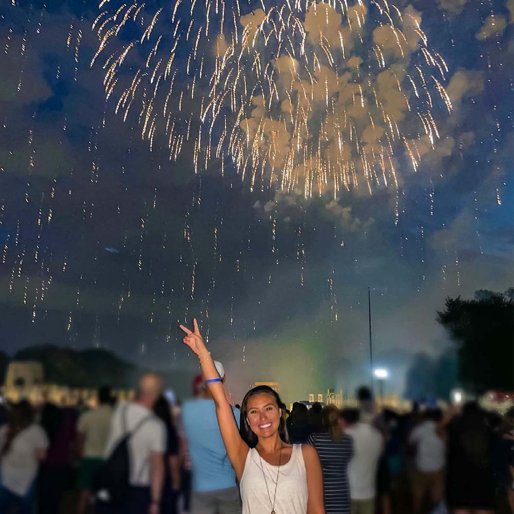 A woman in front of July 4th fireworks.