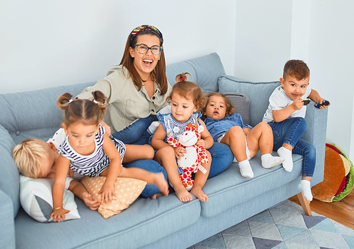A you woman on a sofa with five toddlers