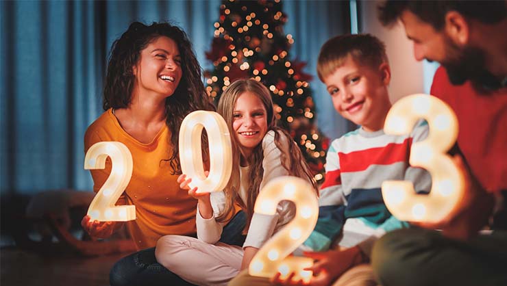 A man, woman, and two kids sit near a Christmas tree.