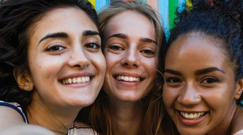 Three young women smile for the camera.