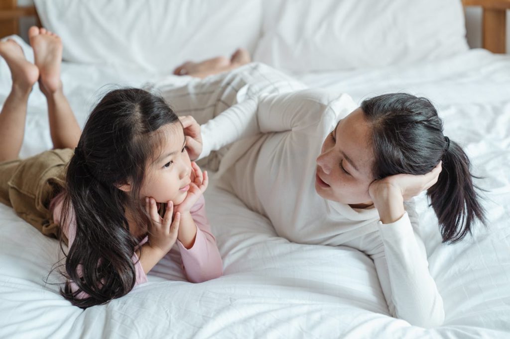 Women and child talking on bed.