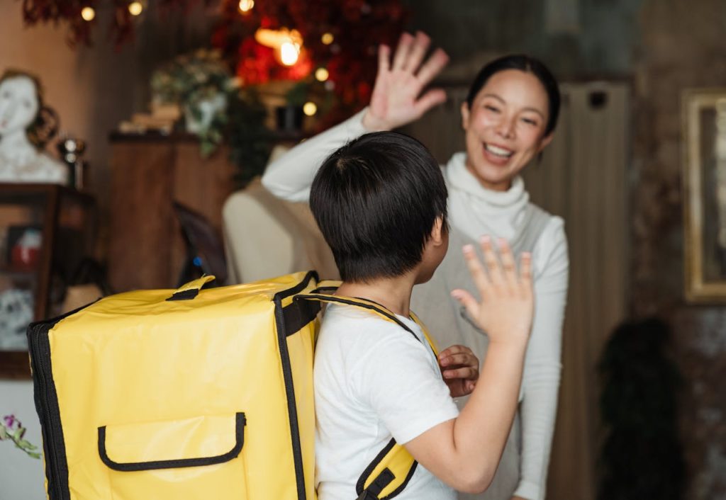 Adult woman and child waving goodbye to each other. 