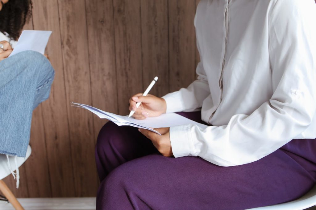 Two women sitting down writing. 